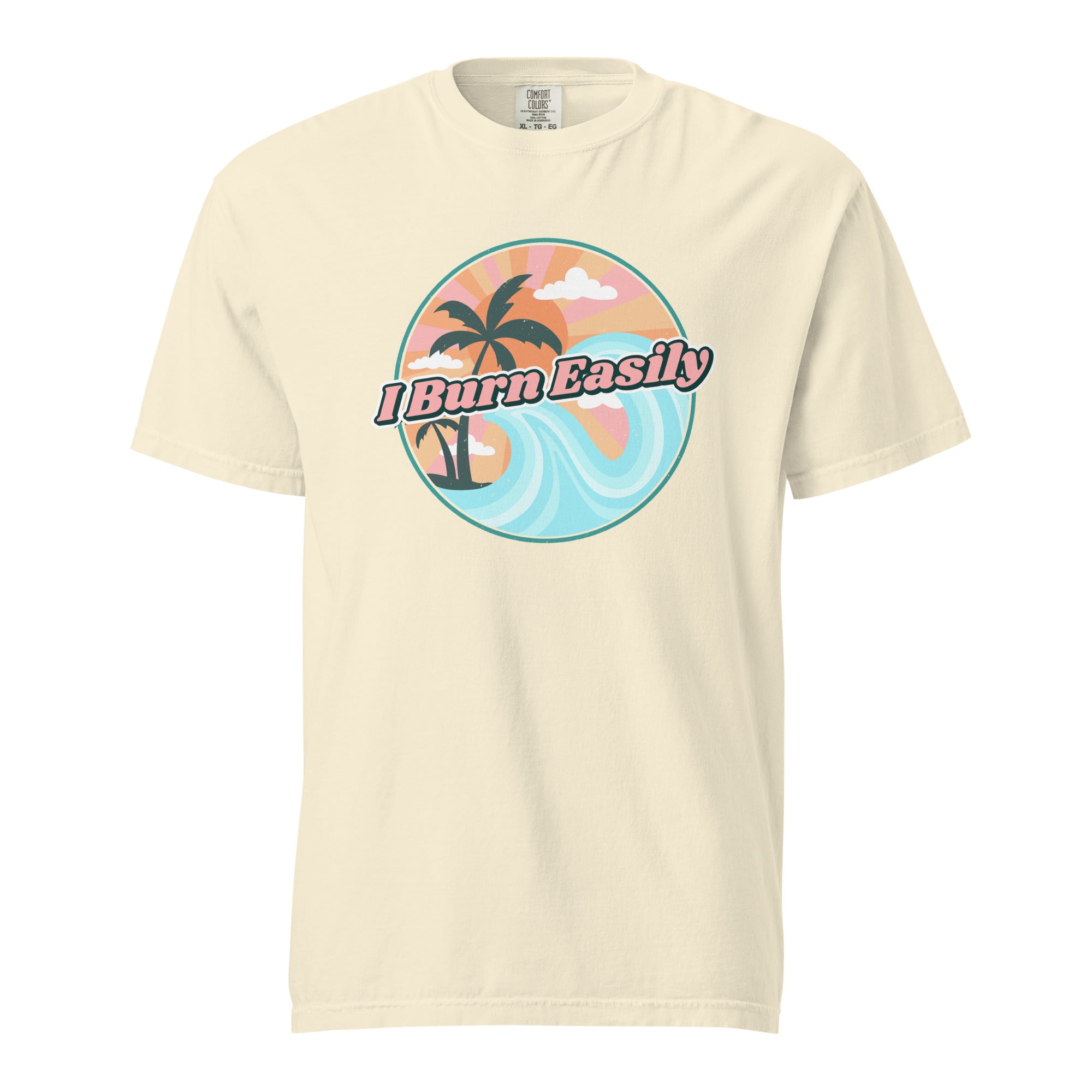 An ivory-colored t-shirt with an illustration of a beach landscape with waves and palm trees with the caption, "I burn easily".